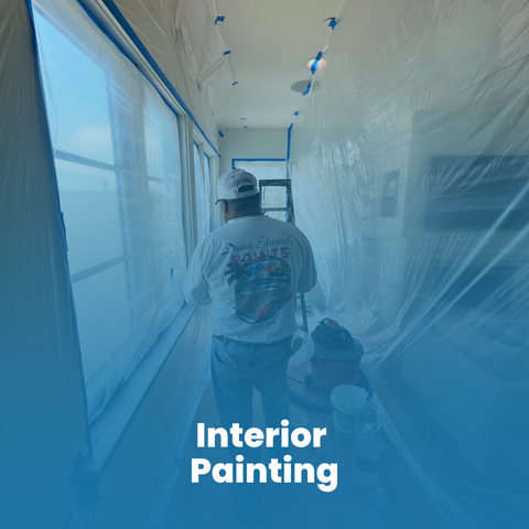 A person on a ladder repairs a hole in a garage ceiling, surrounded by tools and construction materials.