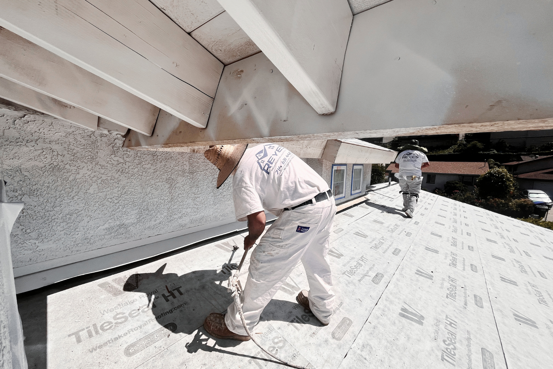 Workers renovate an oceanfront room with floor-to-ceiling glass doors, ladders, and building materials.