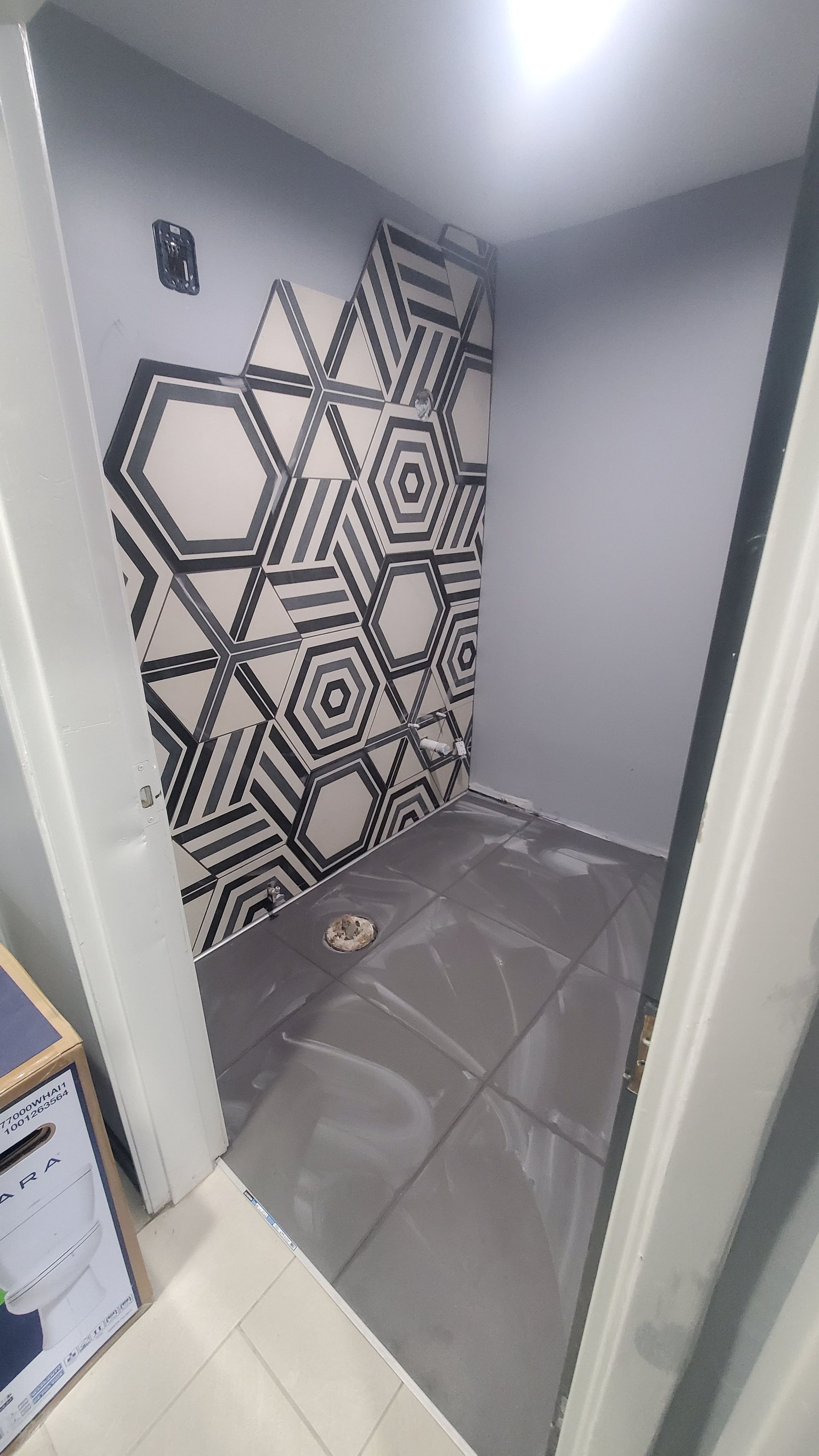 A bathroom with a geometric pattern on the wall and tile floor.