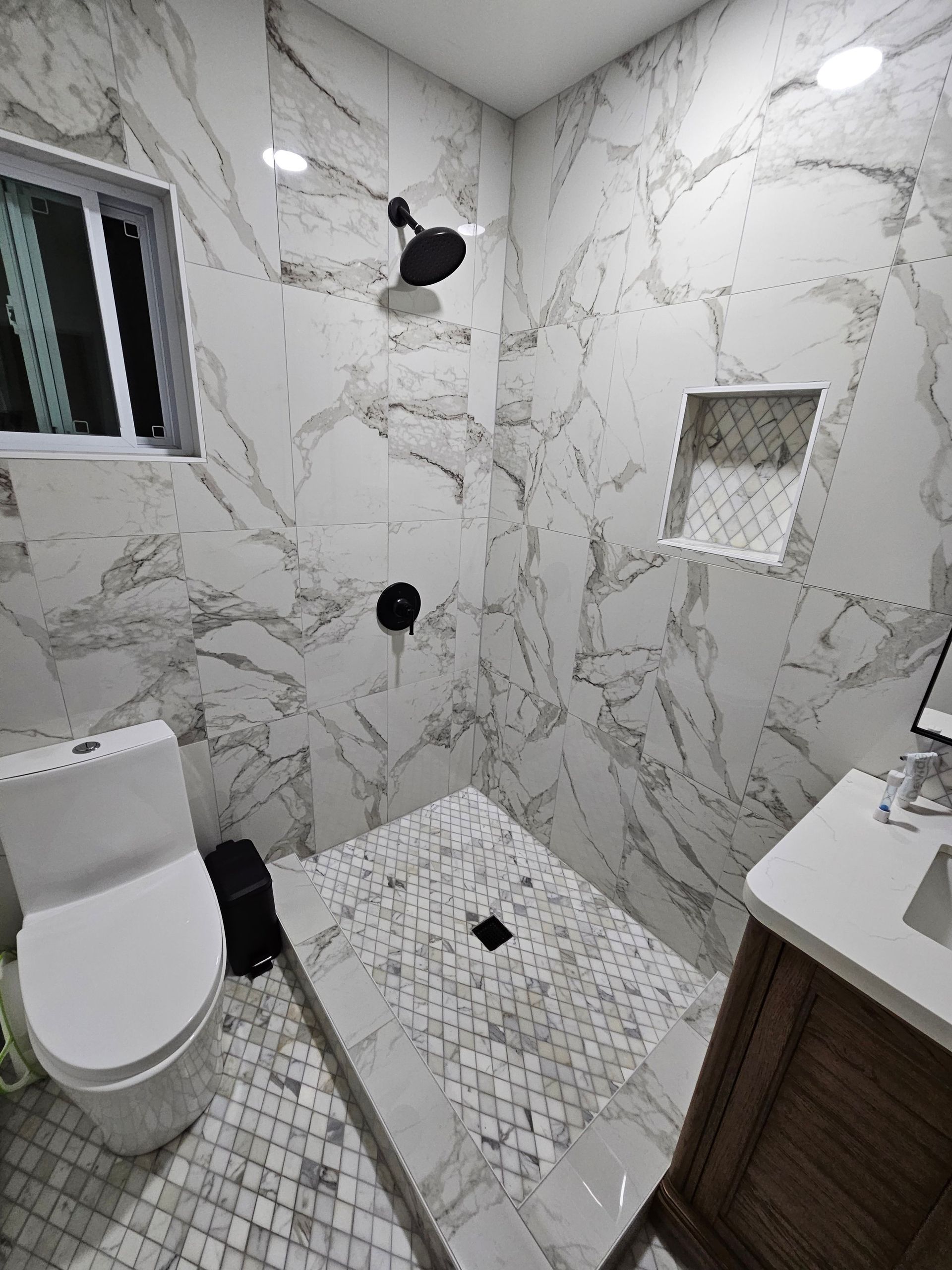 A bathroom with a toilet , sink and shower.