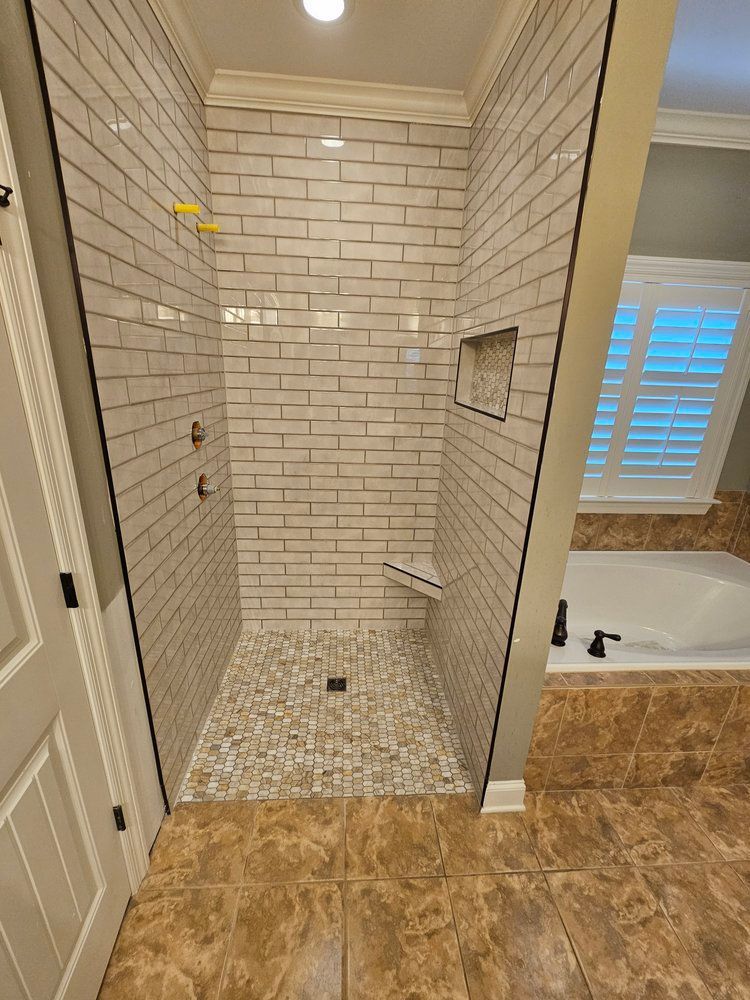 A bathroom with a walk in shower and a tub.