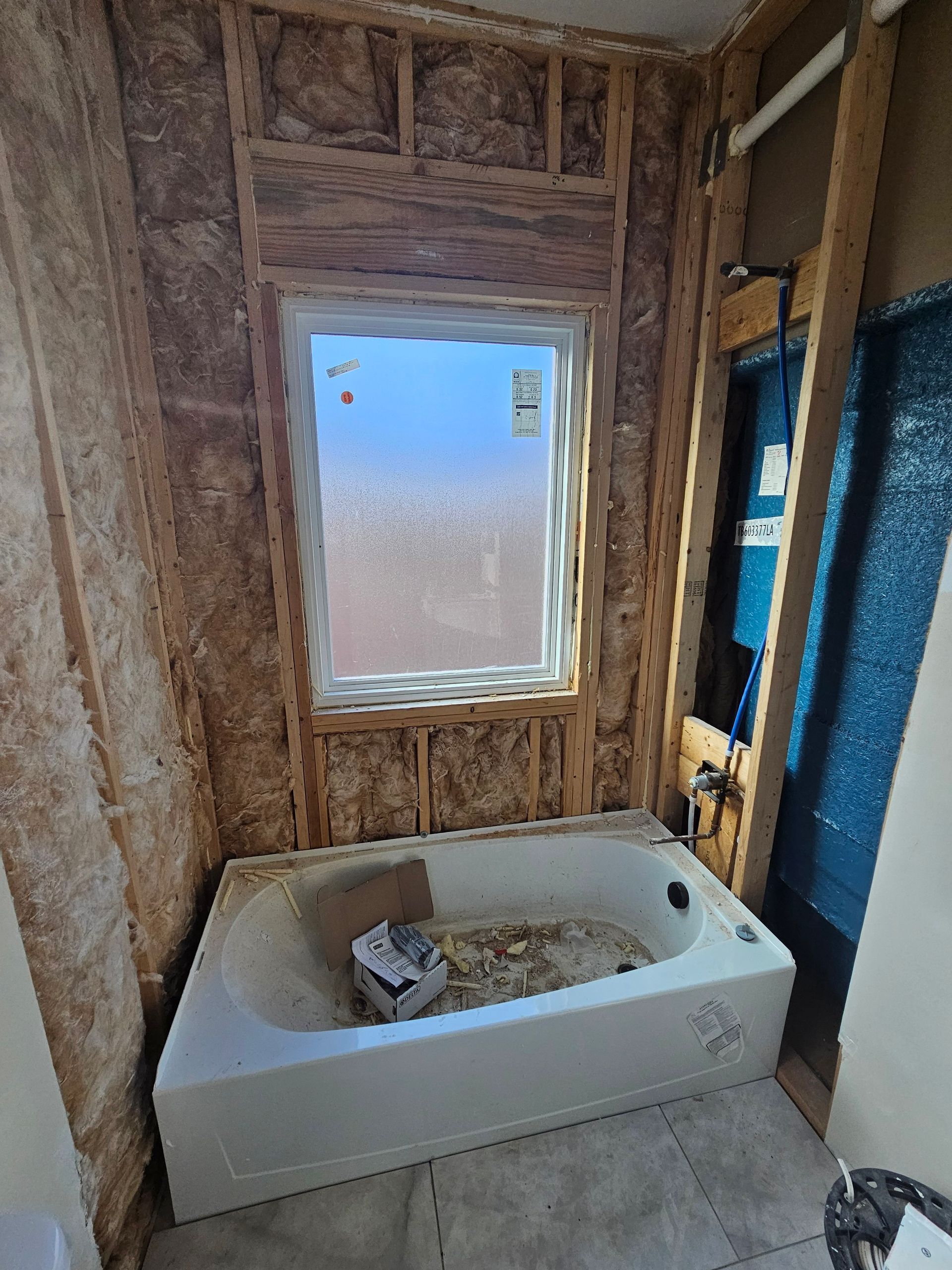 A bathroom under construction with a bathtub and a window.