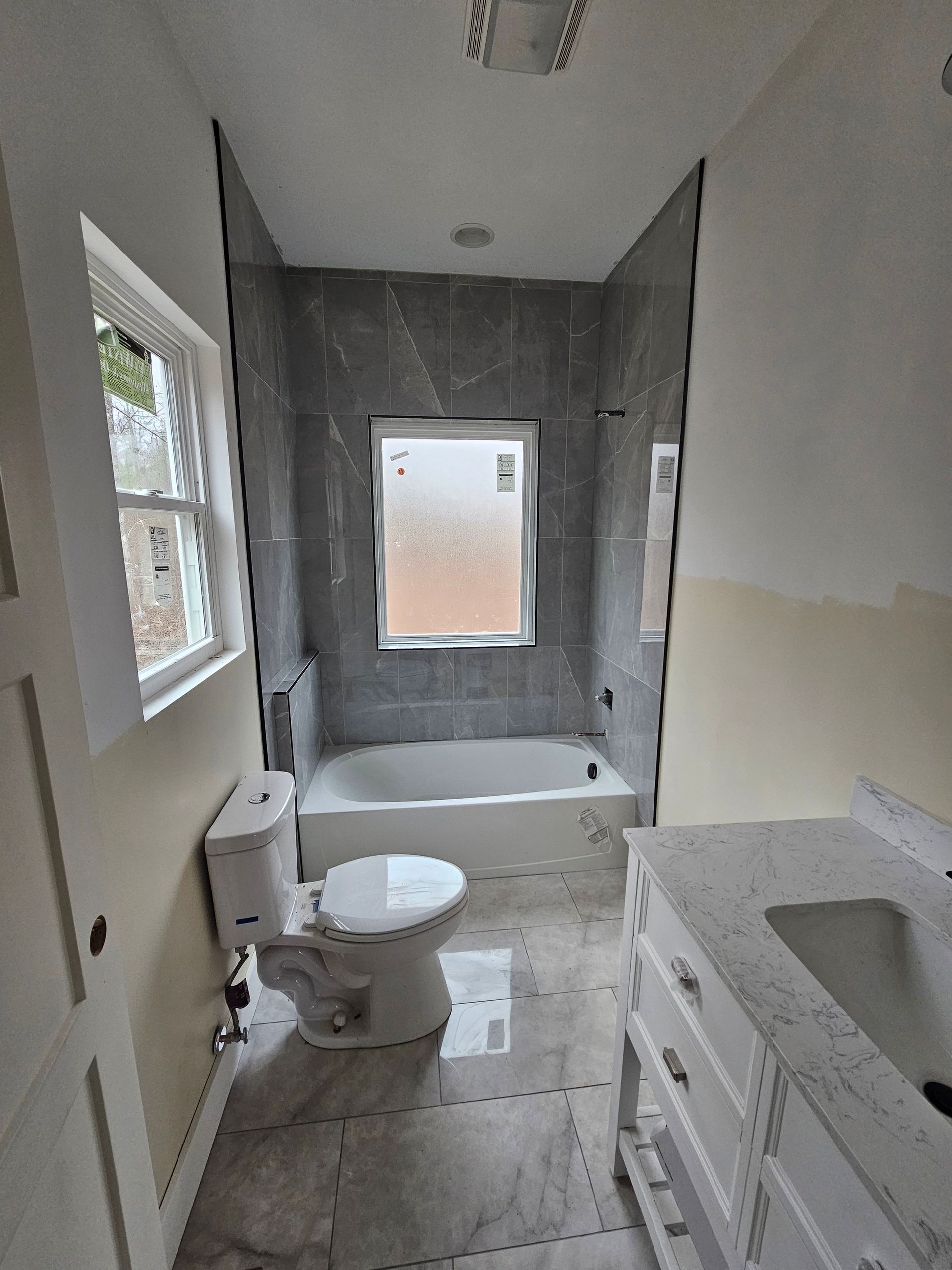 A bathroom with a toilet , tub , sink and window.
