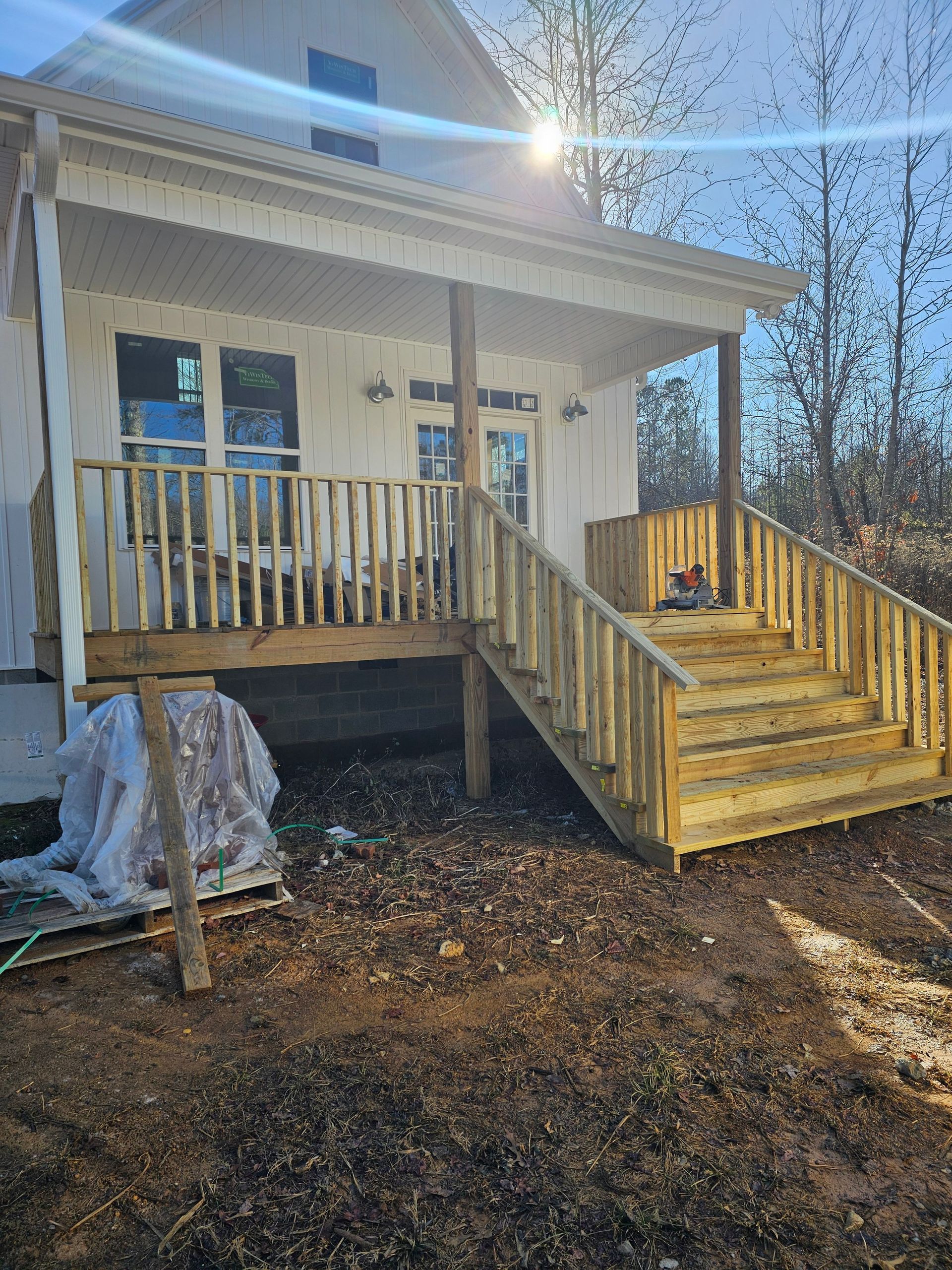 A small white house with a wooden deck and stairs.