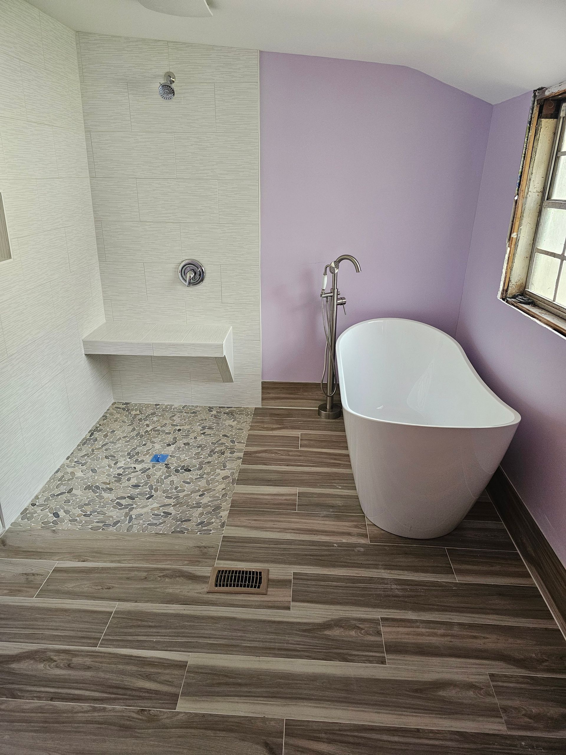 A bathroom with a bathtub , shower , and purple walls.