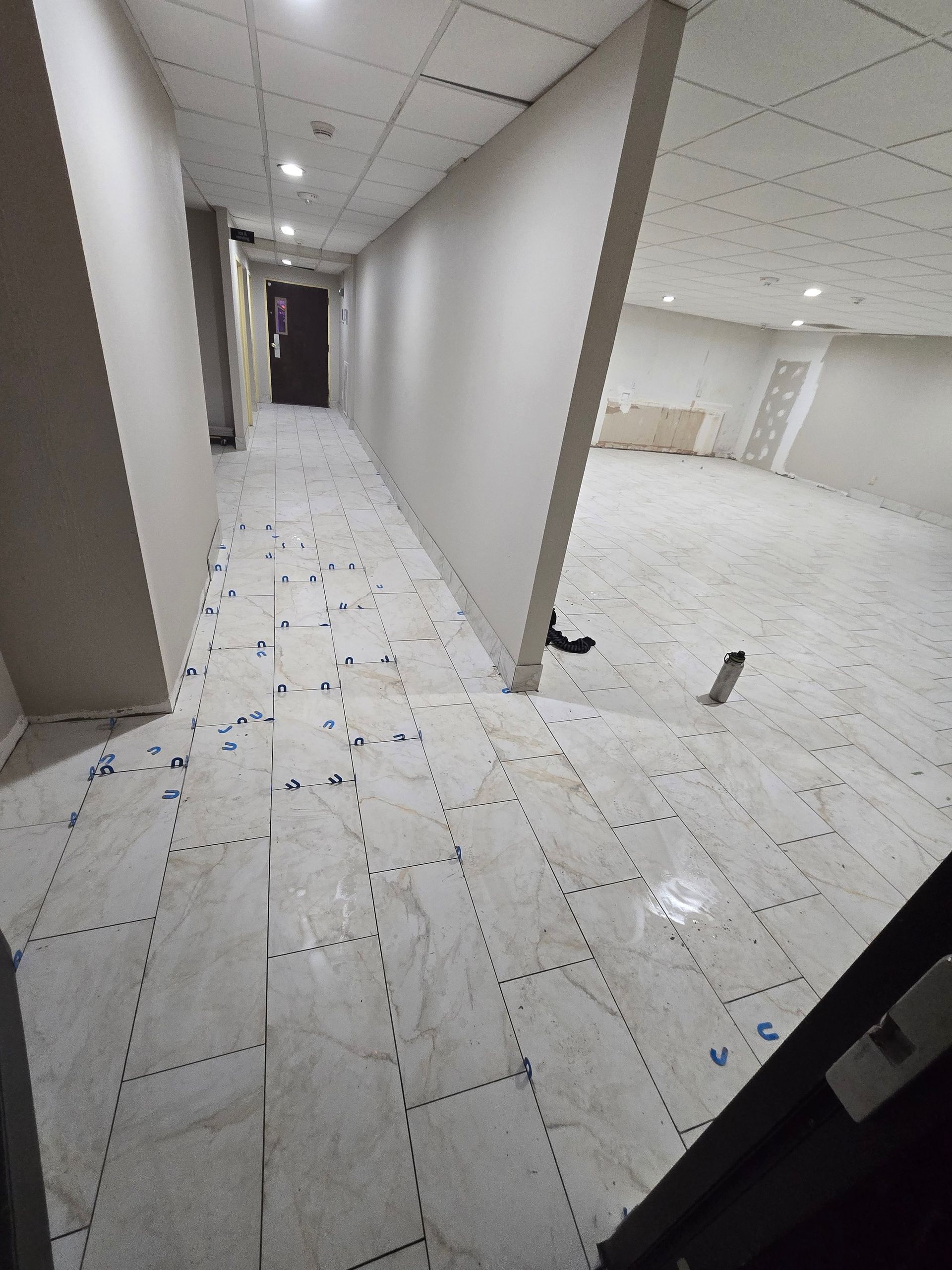 A long hallway with white tiles on the floor