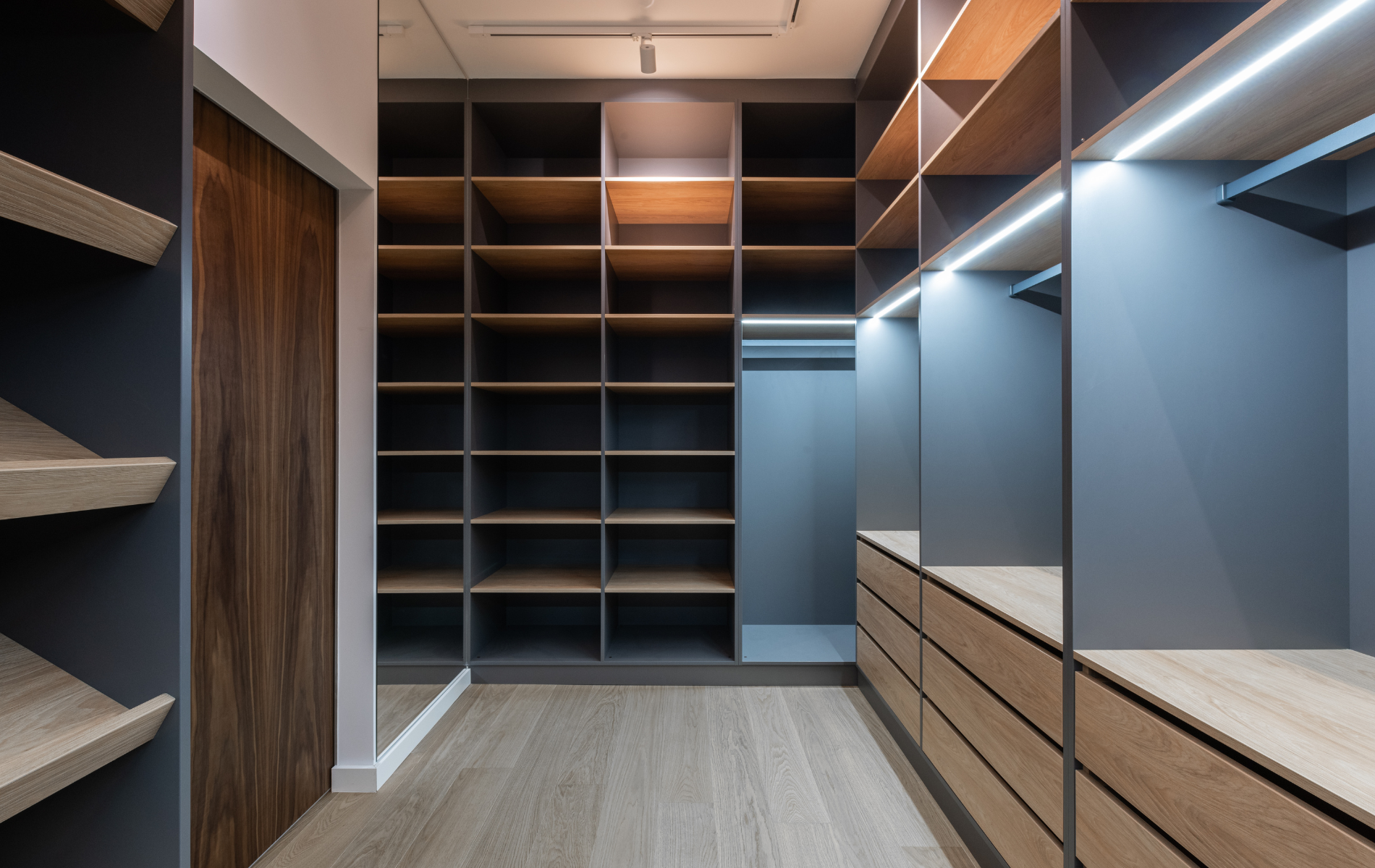 A walk in closet with lots of shelves and drawers.