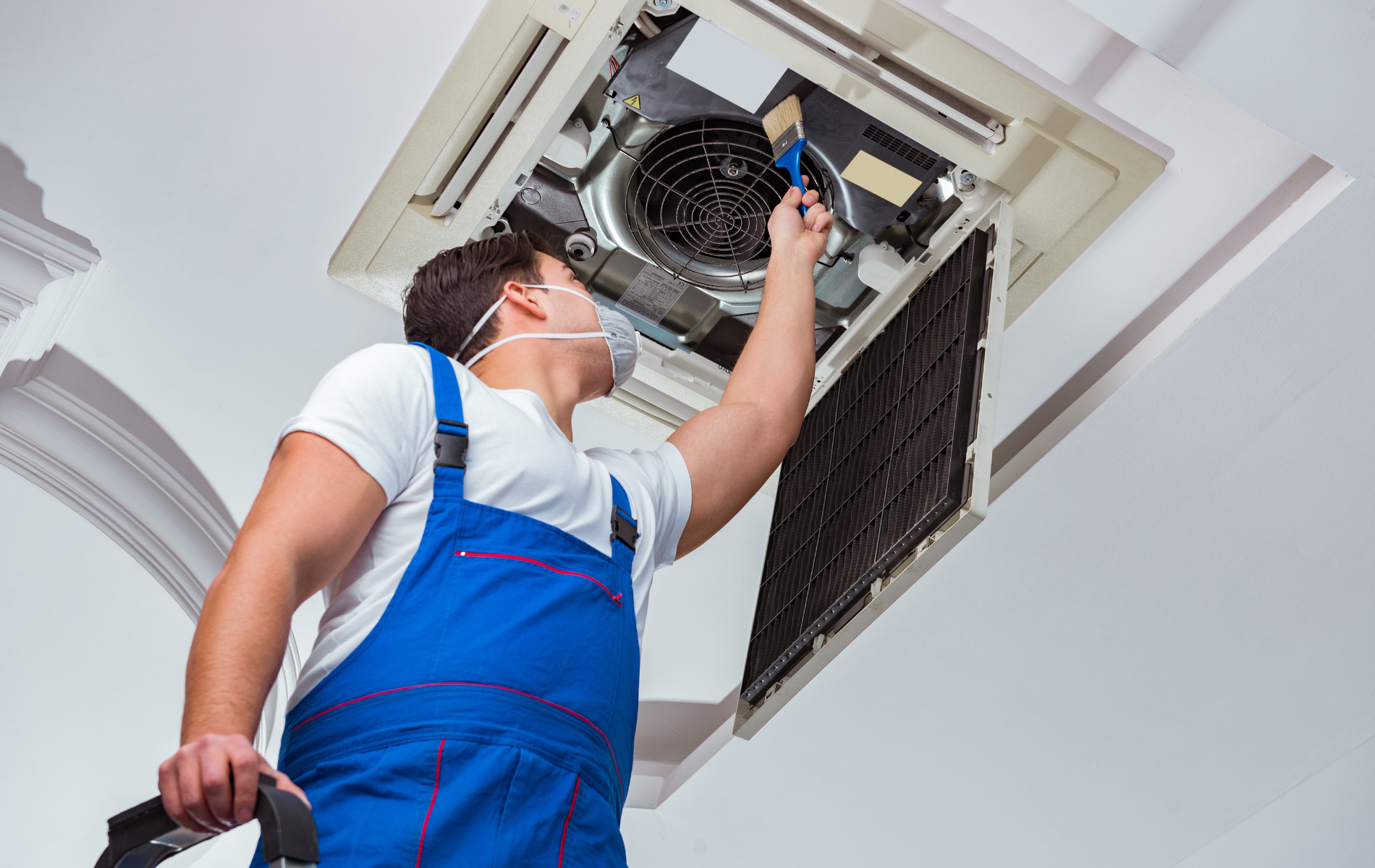 A man wearing a mask is working on an air conditioner.