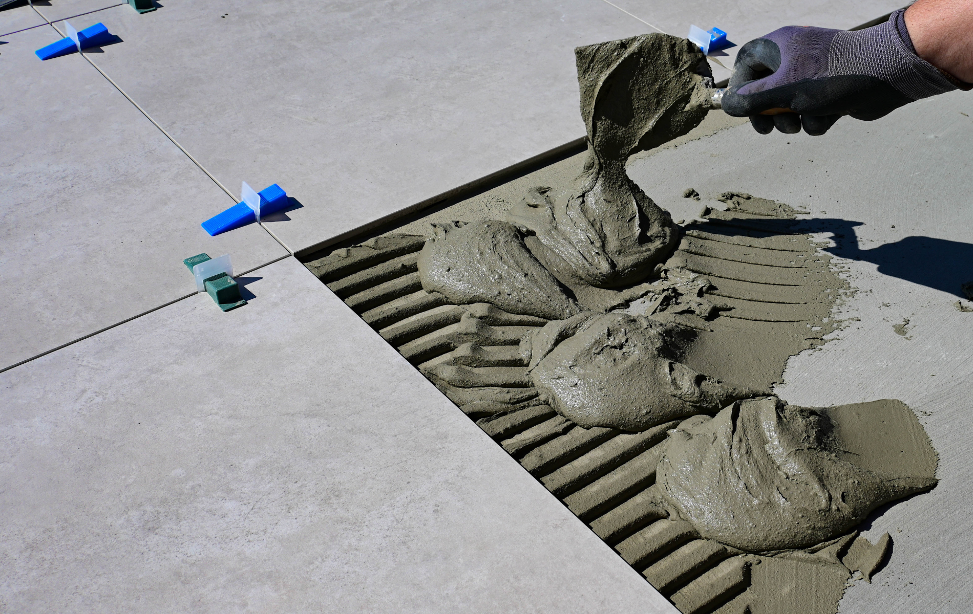 A person is pouring cement on a tile floor.