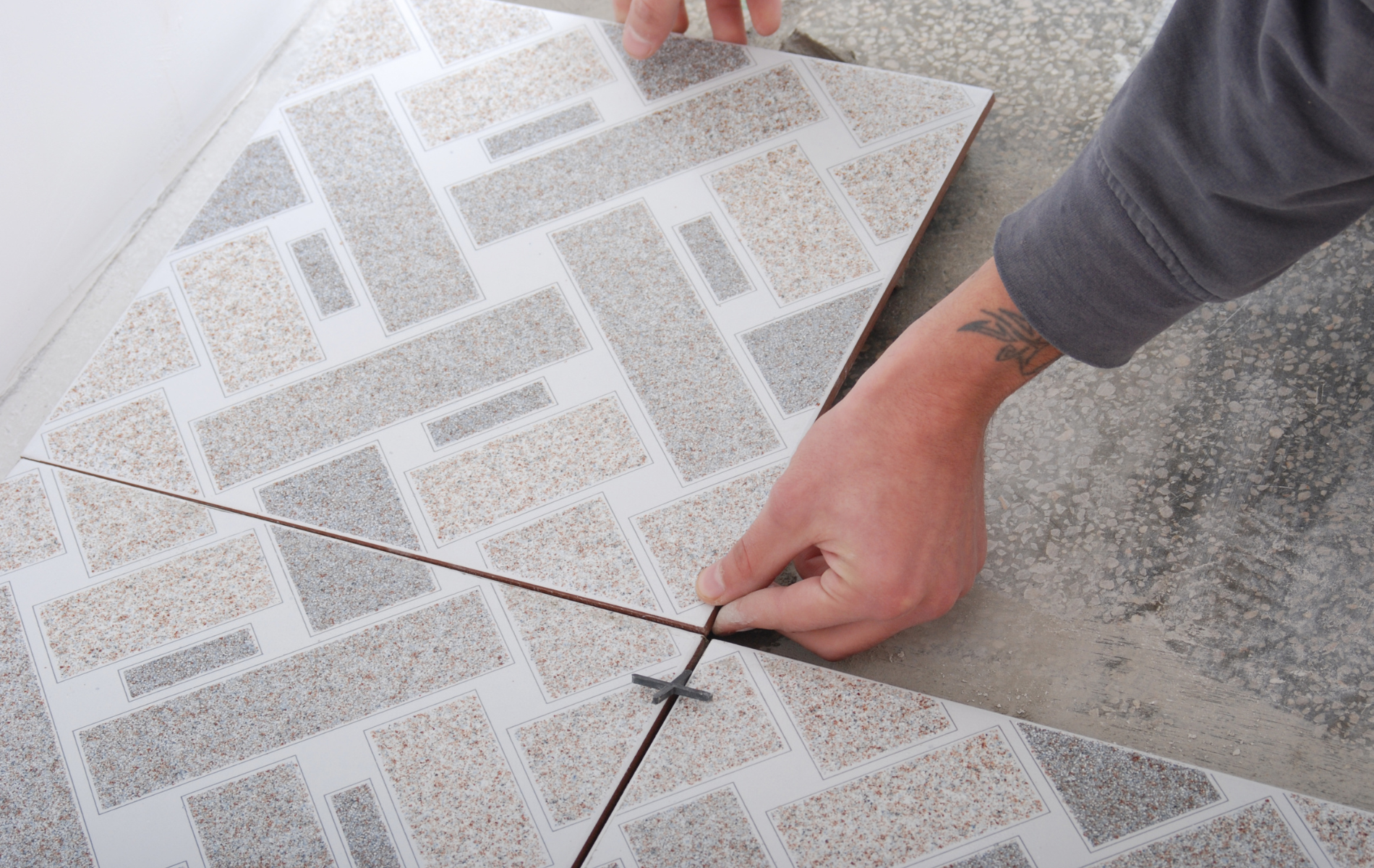 A person is laying a tile on the floor.