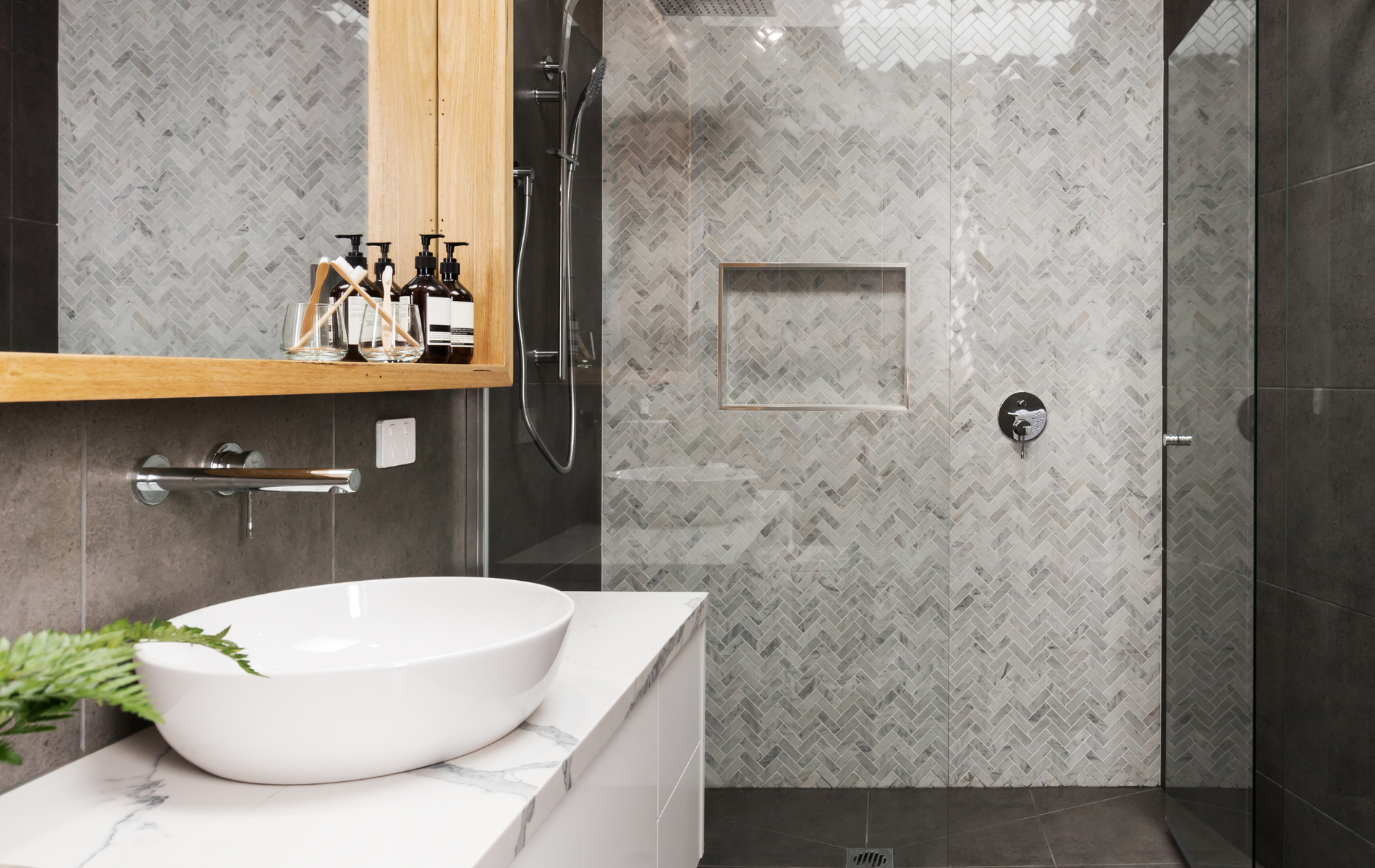 A bathroom with a sink , mirror and walk in shower.
