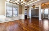 An empty living room with hardwood floors and a chandelier.