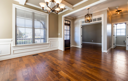 An empty living room with hardwood floors and a chandelier.