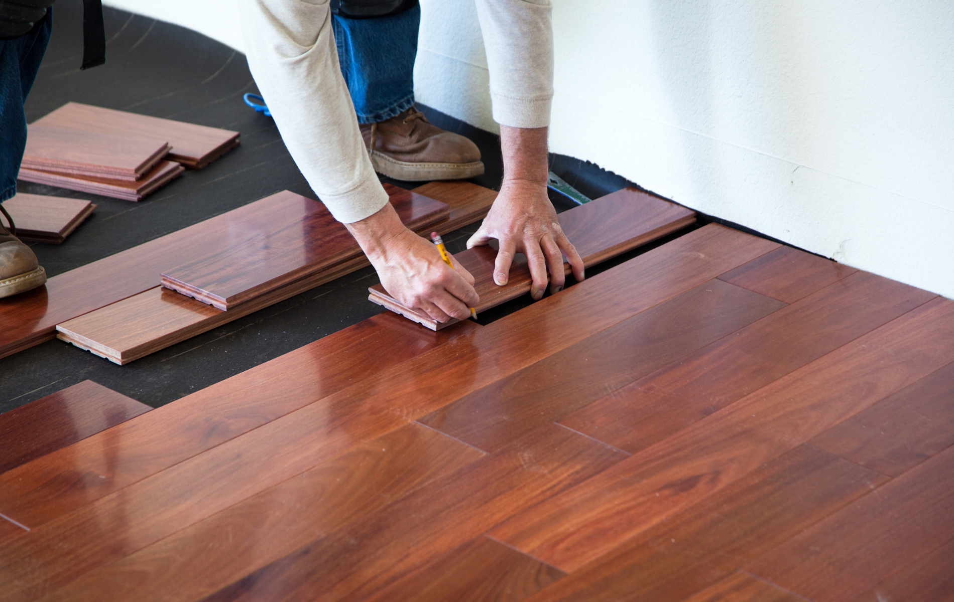 A person is installing a hardwood floor in a room.