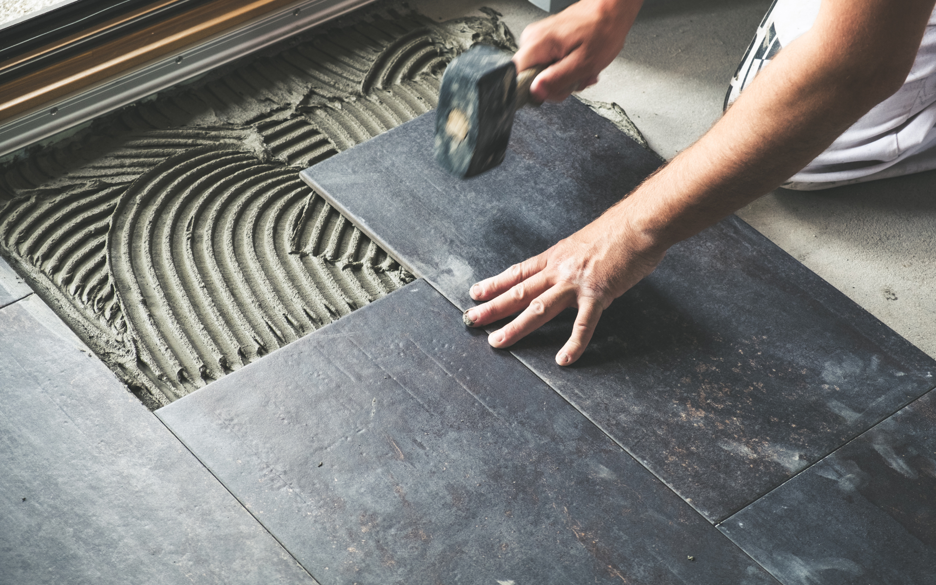 A person is laying a tile on the floor.