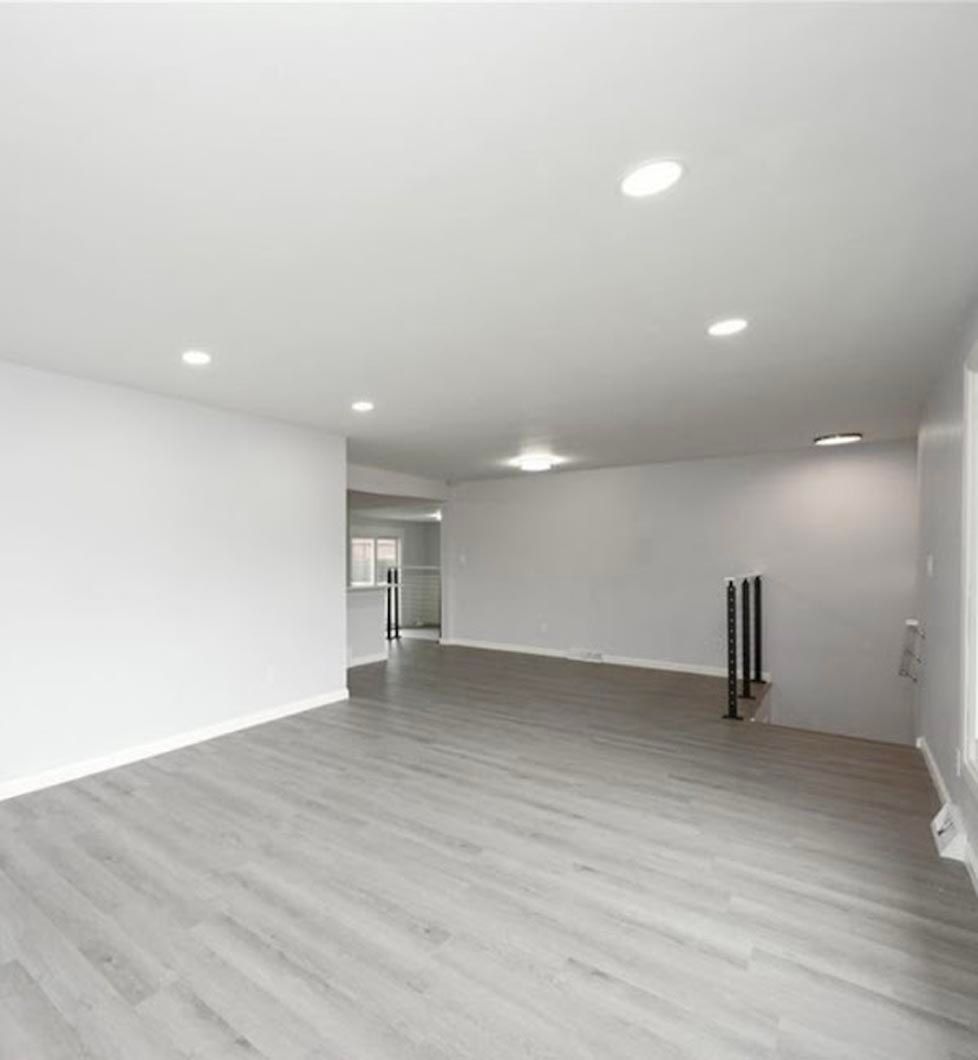 A large empty room with a wooden floor and white walls.