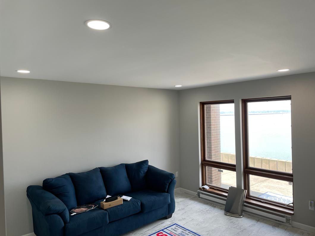 A living room with a blue couch and two windows.