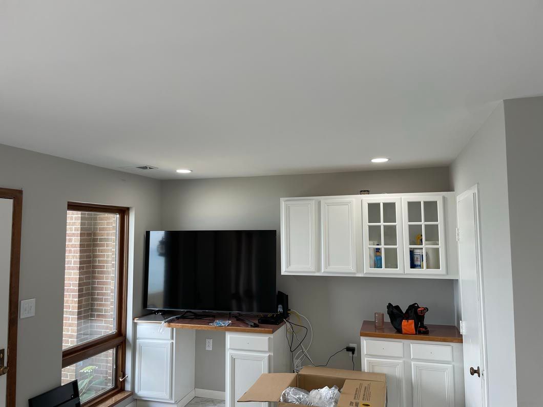 A living room with a flat screen tv and white cabinets.