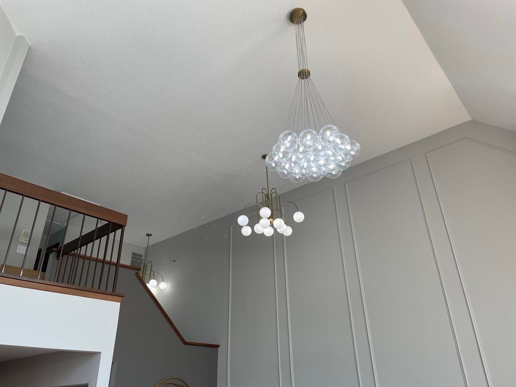 A chandelier is hanging from the ceiling in a room with stairs.