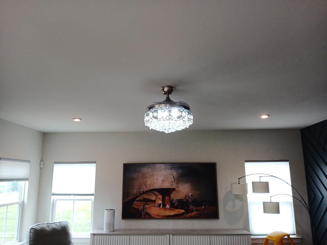 A living room with a painting on the wall and a ceiling fan.