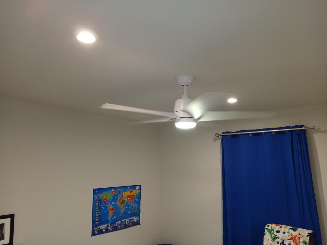 A bedroom with a ceiling fan and a map on the wall