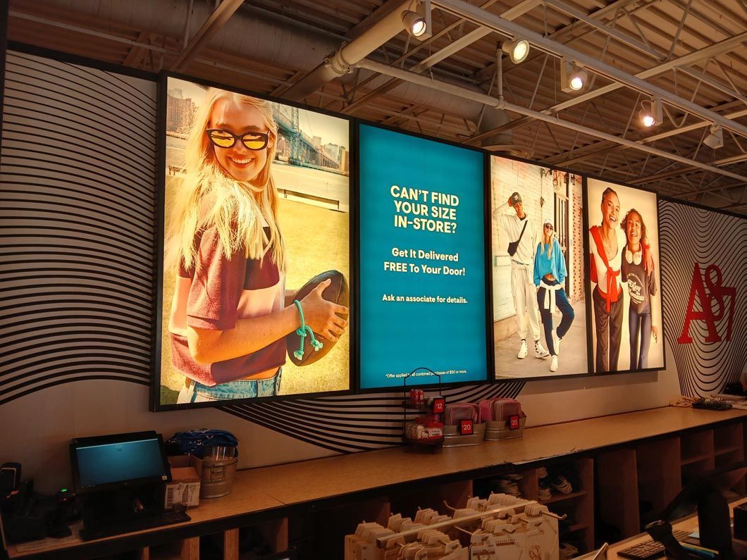 A row of lighted signs are hanging on a wall in a store.
