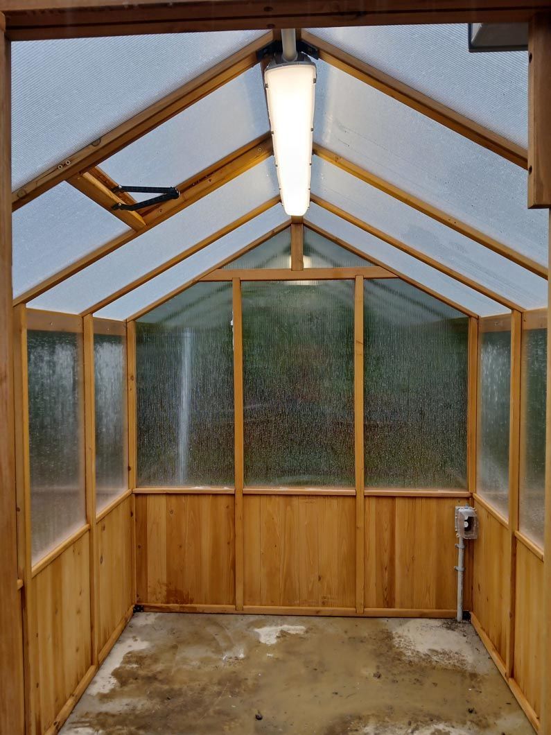 A greenhouse with wooden walls and clear plastic roof