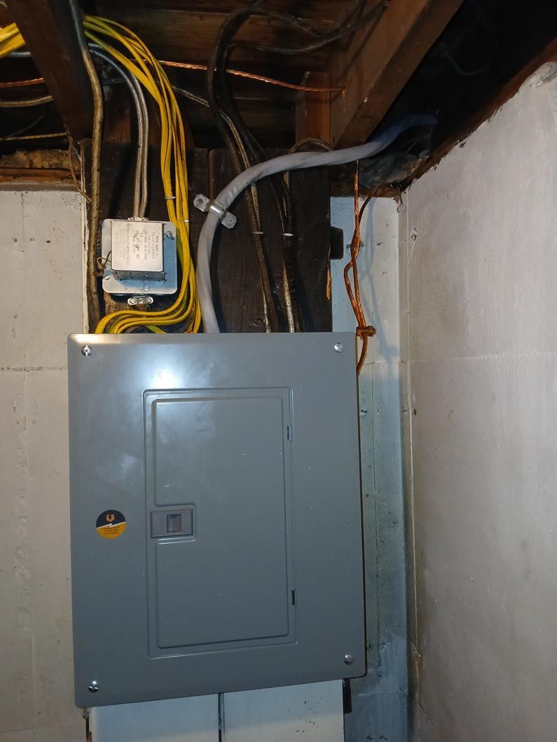 A electrical box is hanging on a wall in a basement.