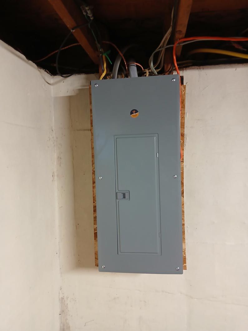 A gray electrical box is hanging on a white wall.