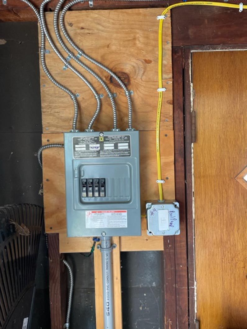 A electrical box is hanging on a wooden wall next to a door.
