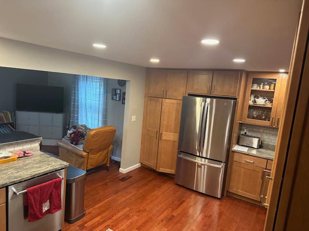 A kitchen with hardwood floors , stainless steel appliances and a refrigerator.