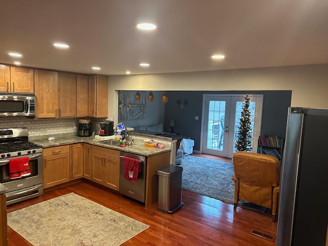 A kitchen with wooden cabinets and stainless steel appliances and a christmas tree in the background.