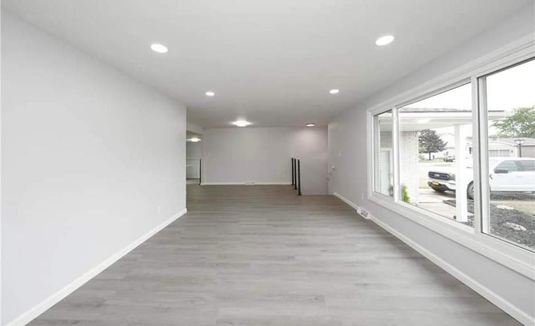An empty hallway with hardwood floors and a large window.
