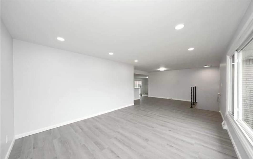 An empty living room with hardwood floors and white walls.