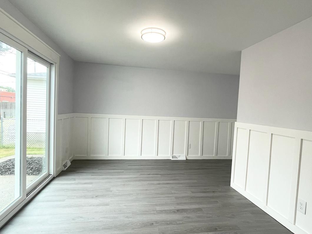 An empty room with hardwood floors and sliding glass doors.