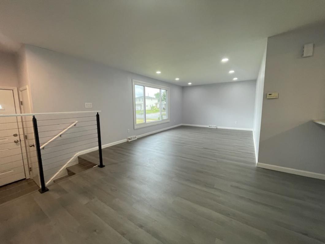 An empty living room with hardwood floors and stairs leading up to the second floor.