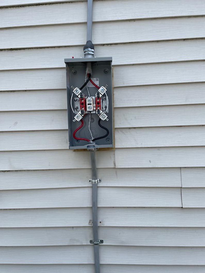 An electrical box is attached to the side of a house.