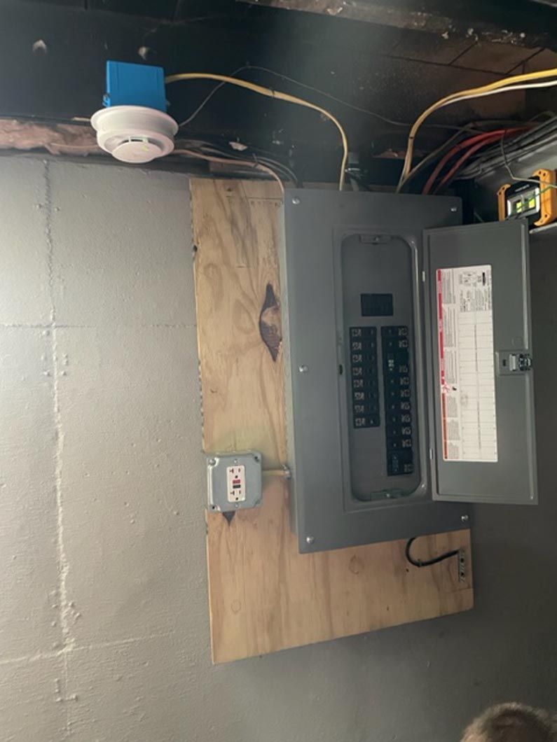 A smoke detector is hanging from the ceiling above a electrical box.