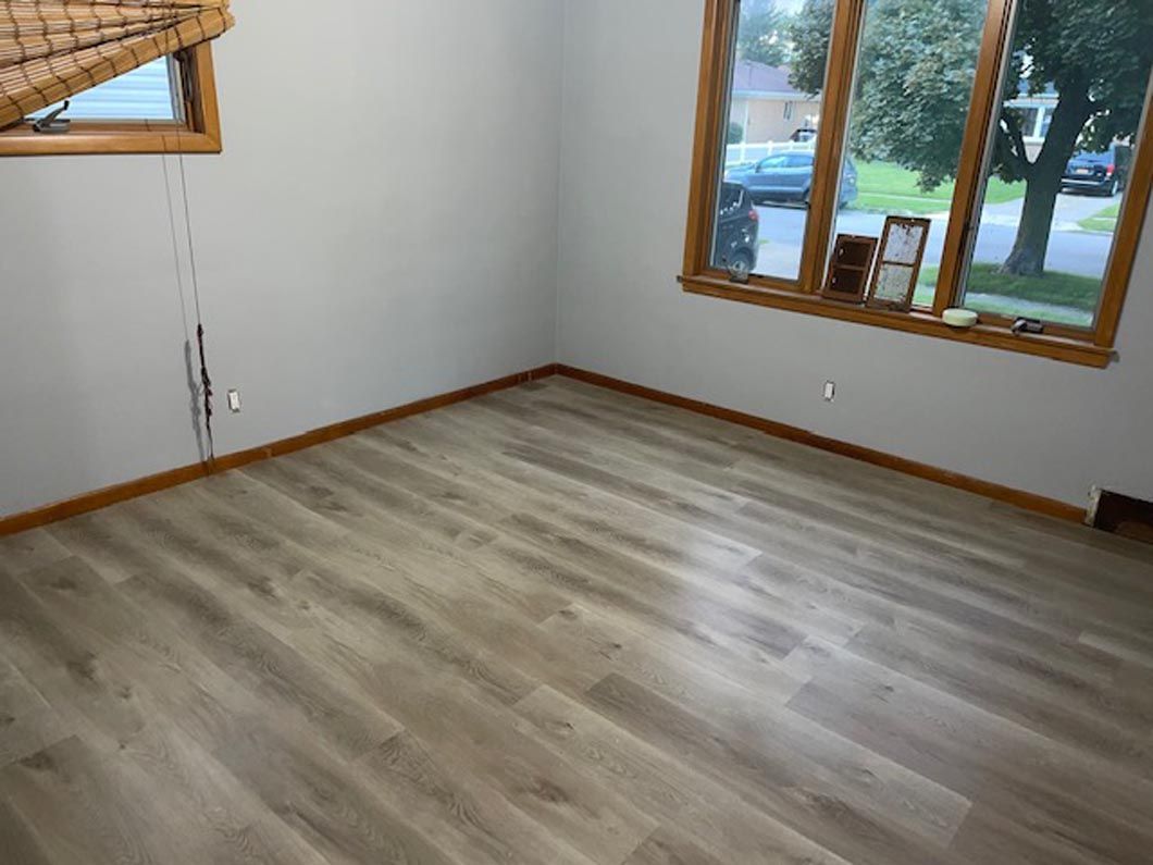 A room with hardwood floors and two windows.