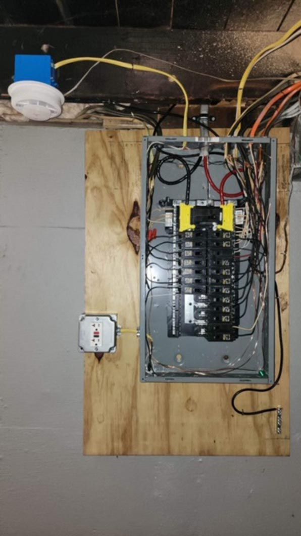 A electrical box is hanging on a wooden wall.