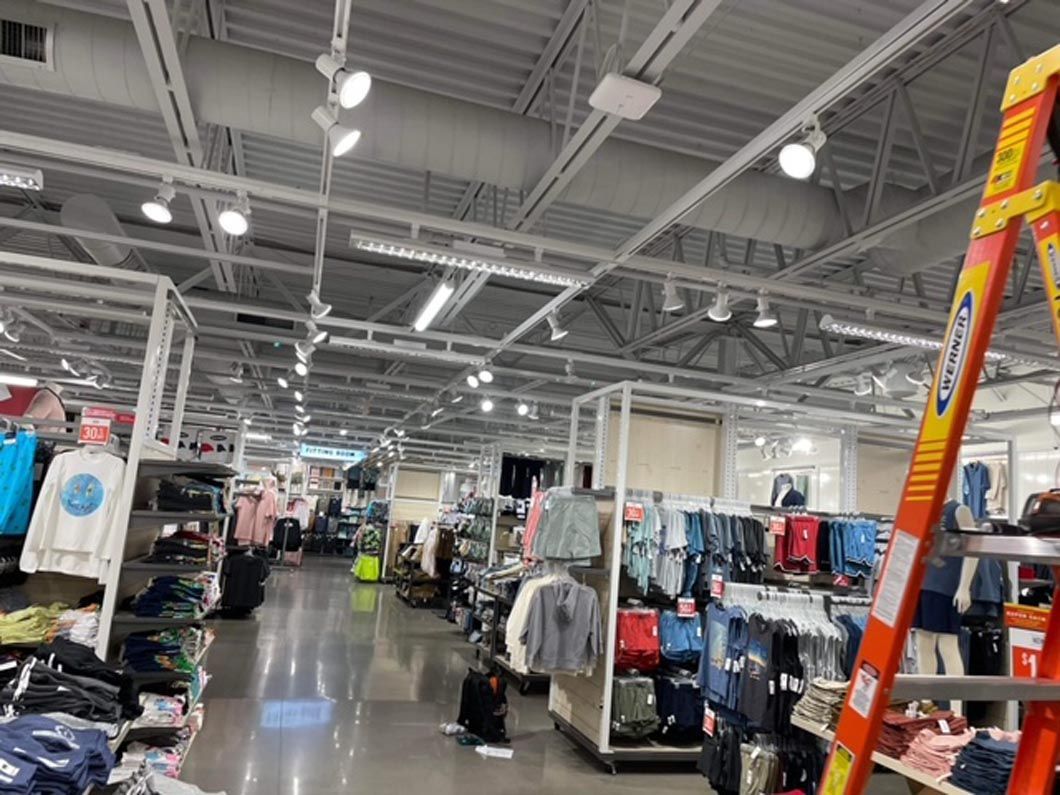 A ladder is sitting in the middle of a clothing store.
