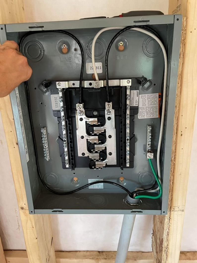 A person is opening a electrical box with wires coming out of it.