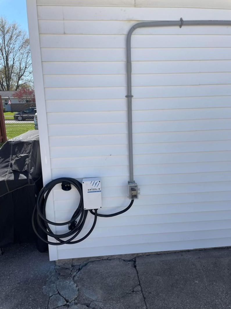 A power cord is attached to the side of a white house.