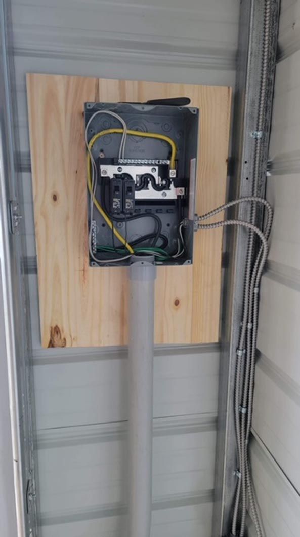 A box with wires coming out of it is hanging on a wall.