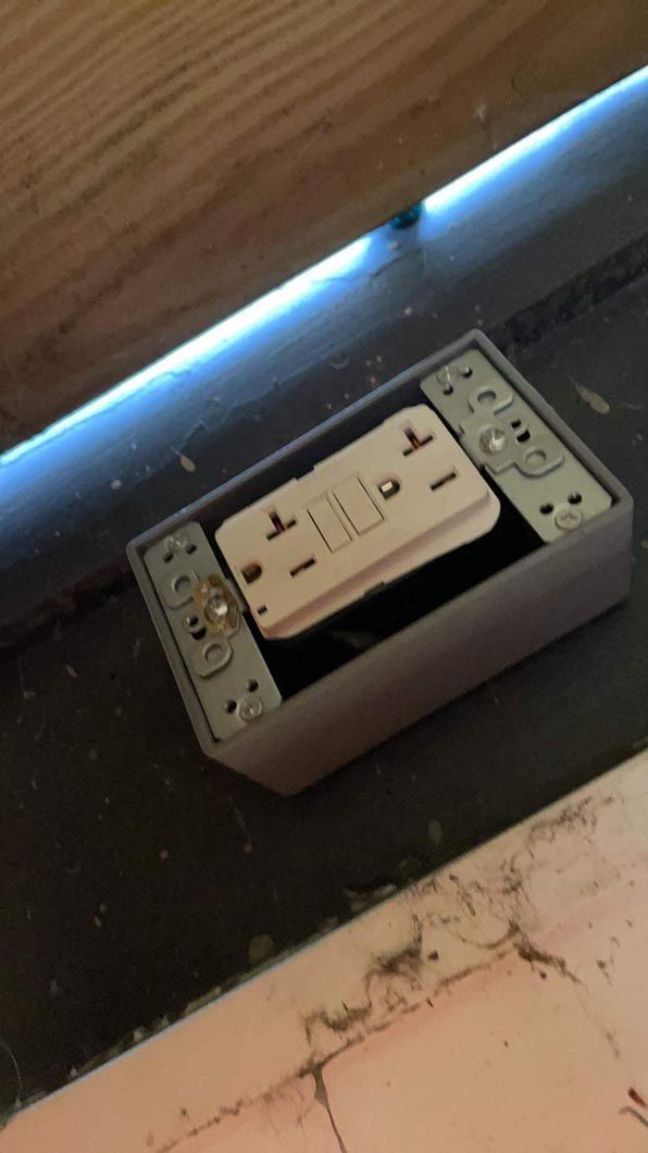 A white electrical outlet is sitting on a tiled floor