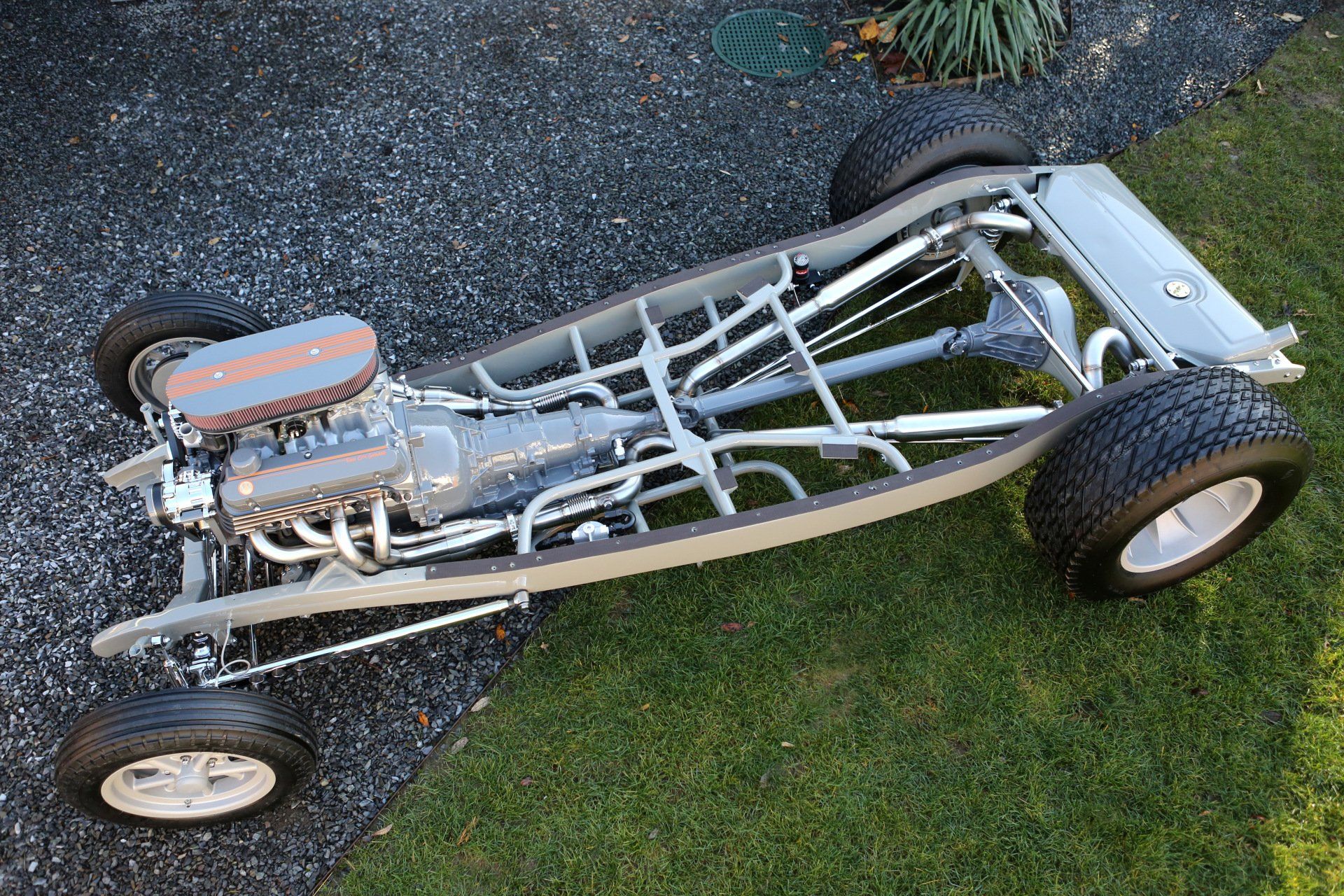 A hot rod is sitting on top of a lush green field.