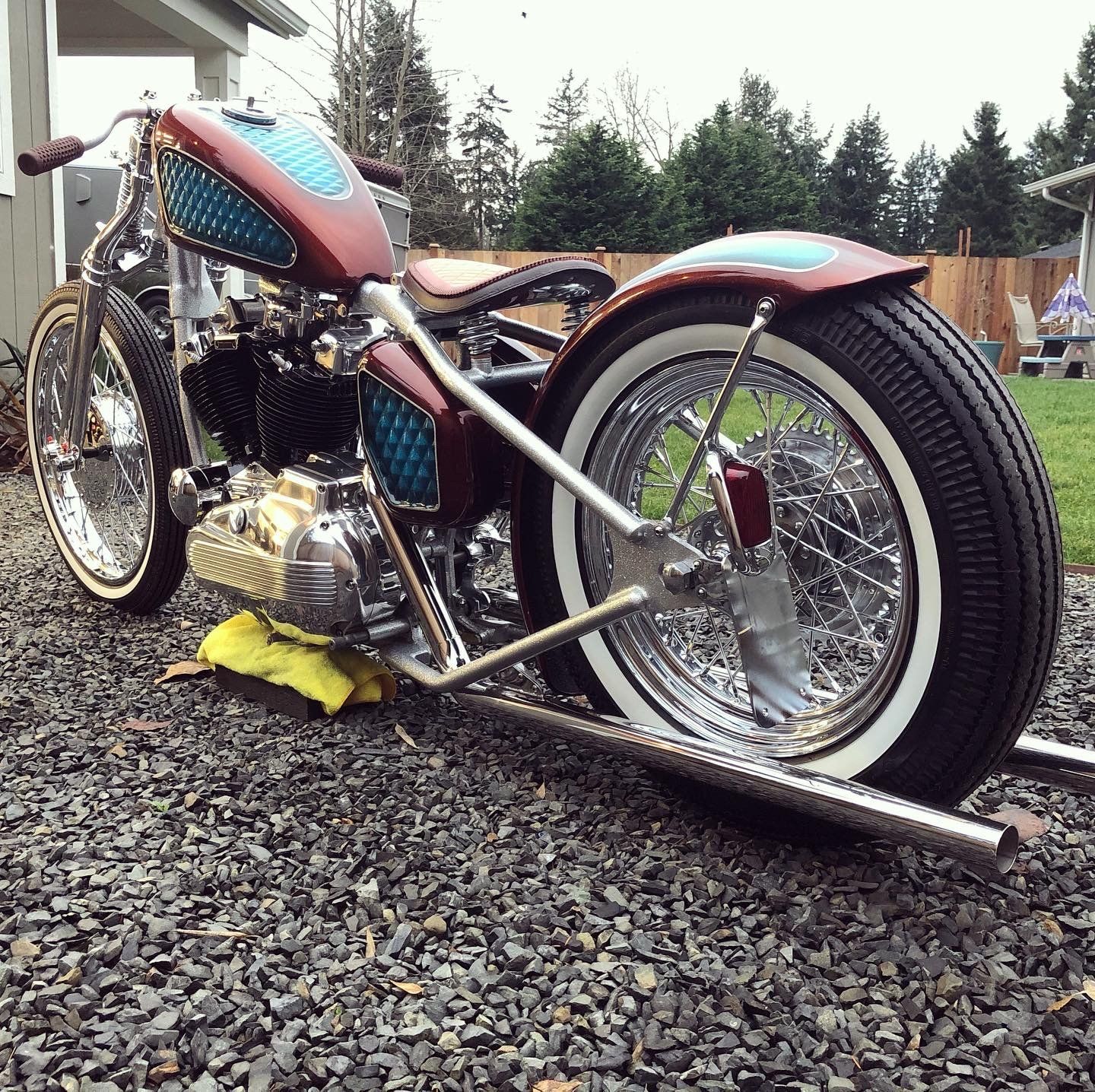 A motorcycle is parked on gravel in front of a house