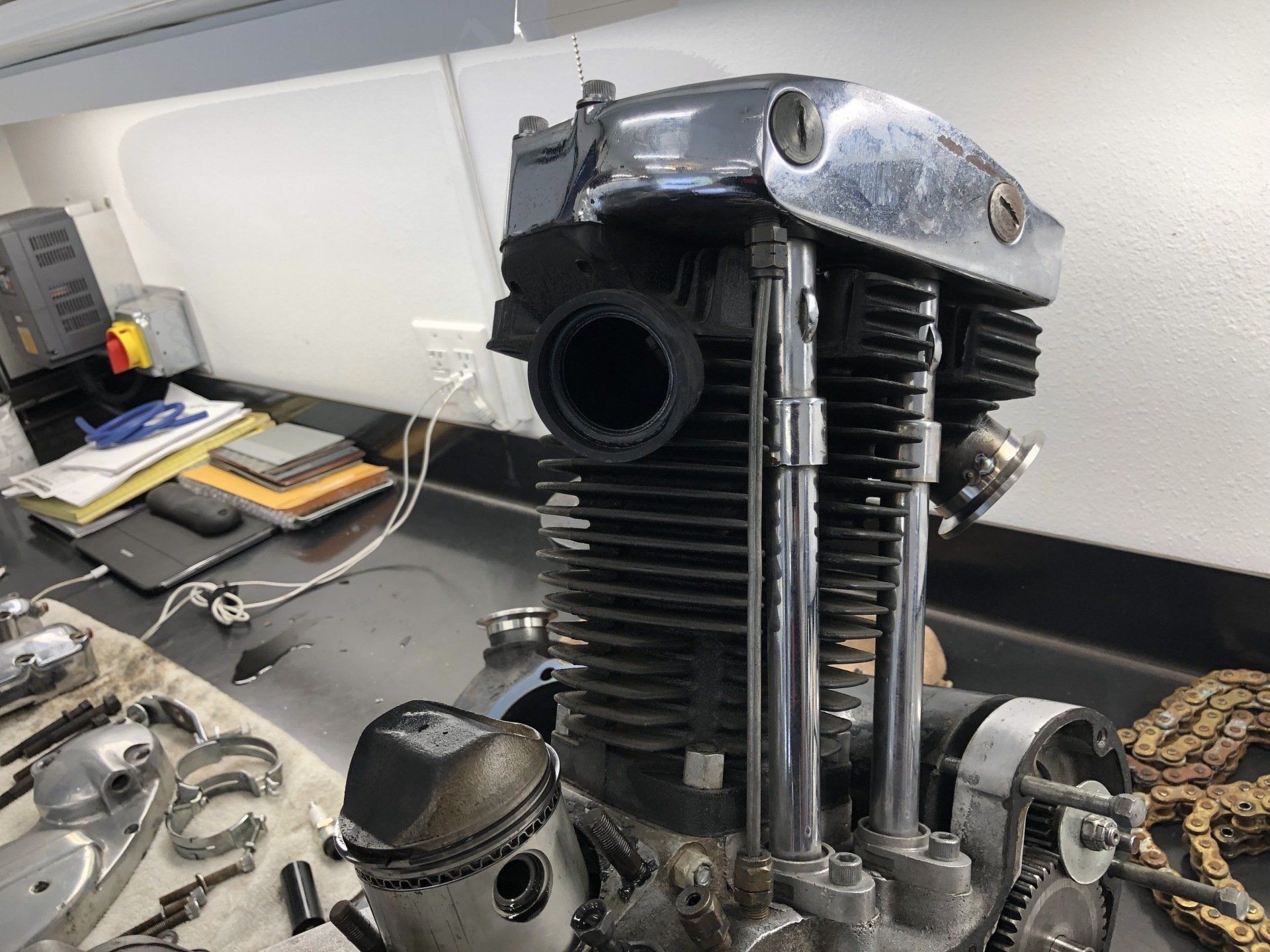 A motorcycle engine is sitting on a table in a garage.