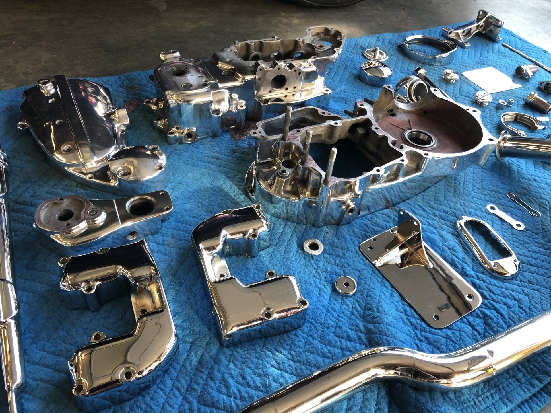 A bunch of chrome parts are laying on a blue blanket