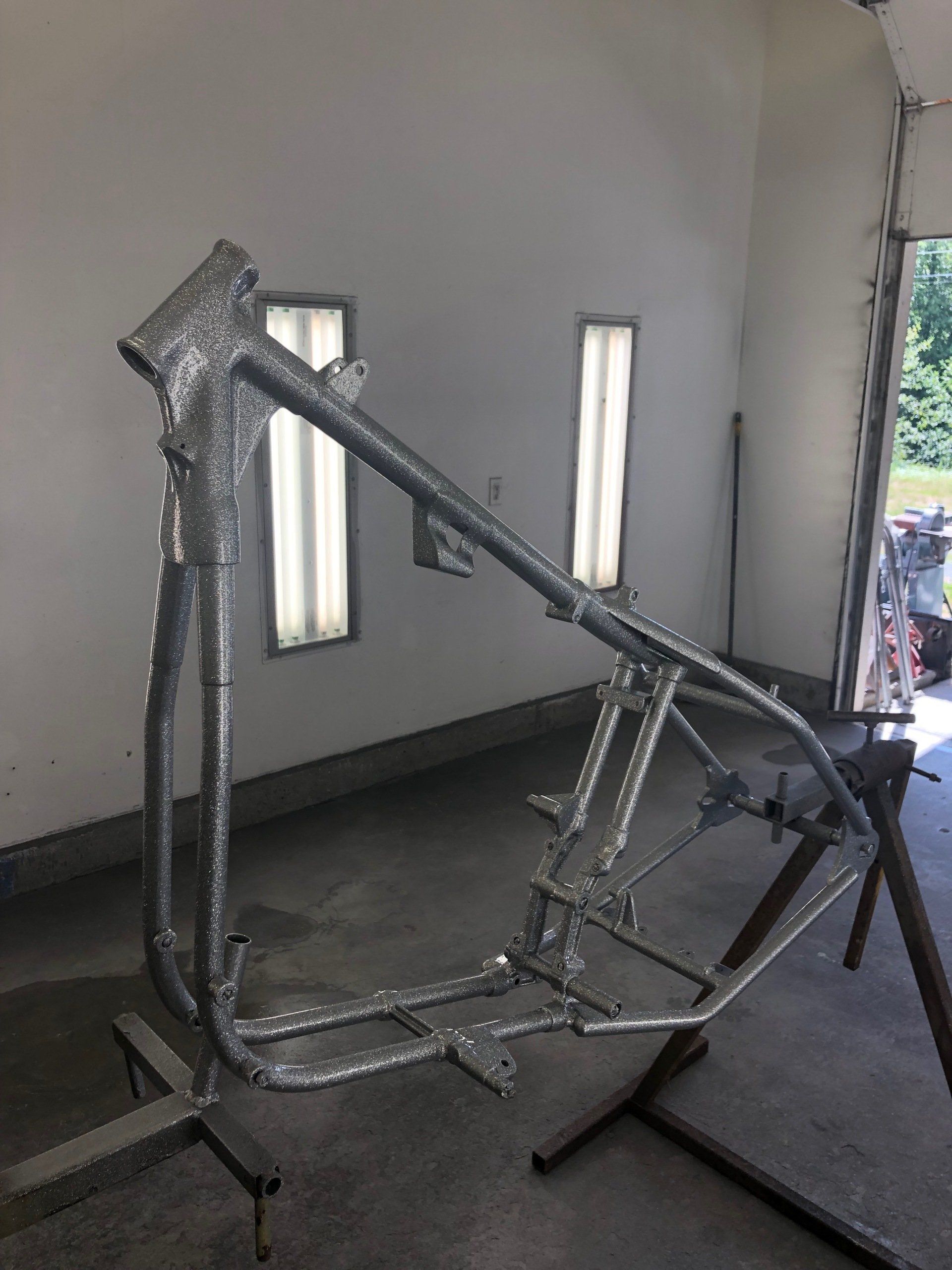A motorcycle frame is sitting on a stand in a garage.